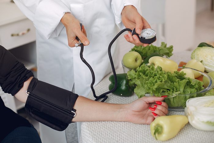 Doctor measures the pressure of the patient in the kitchen