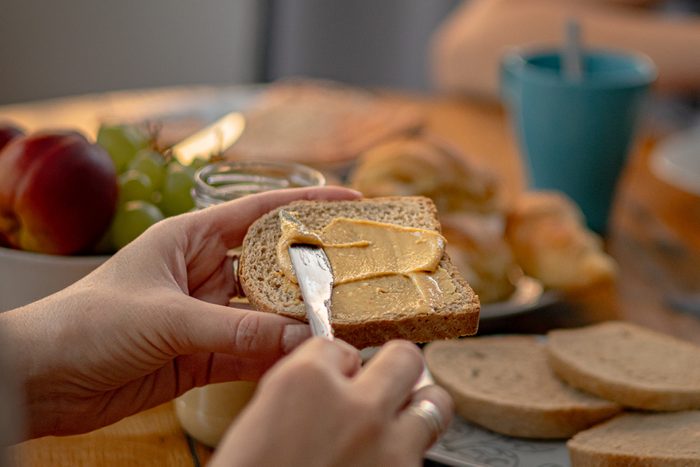 spreading peanut butter on wholegrain bread