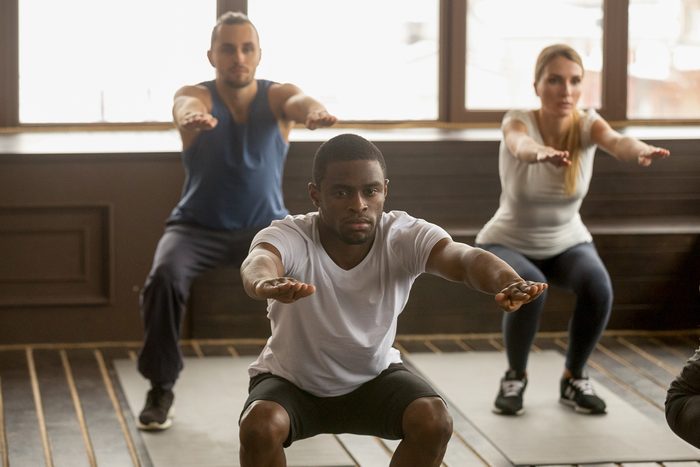 man doing squat exercise at group fitness training
