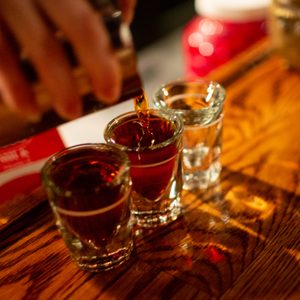 Whiskey Being Poured Into Shot Glasses On Bar