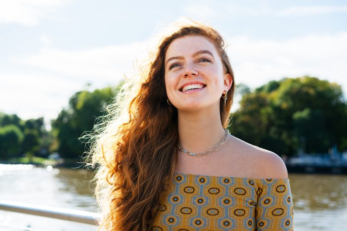 Woman smiling looking up next to river