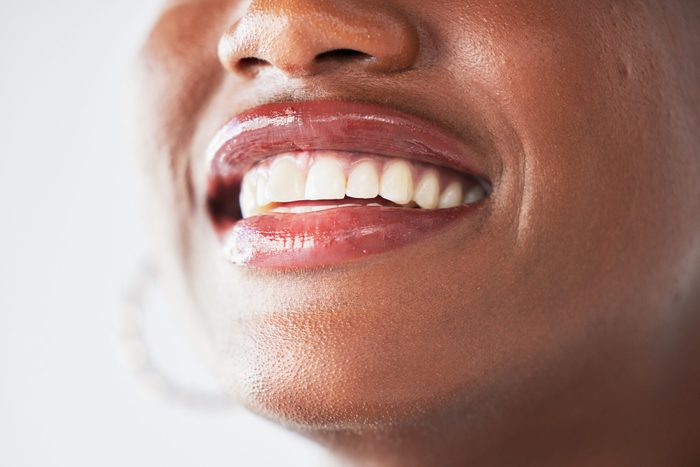 Happy, lips and beauty with a woman closeup in studio on a gray background for makeup or cosmetics. Smile, mouth and teeth with a confident female person posing to promote dental health or hygiene