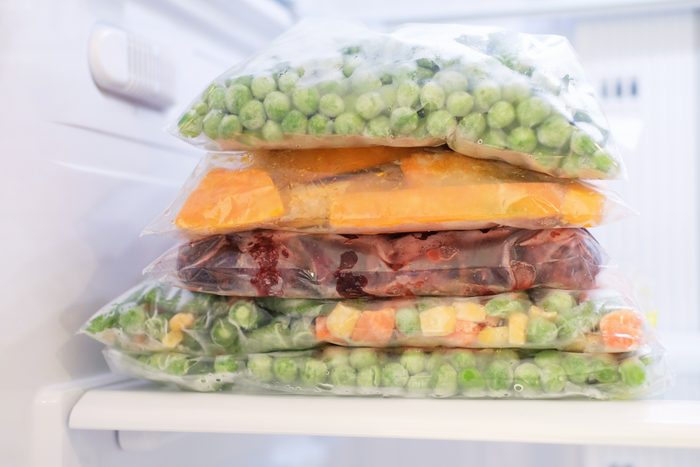 Cellophane bags with colorful frozen vegetables in freezer front view.