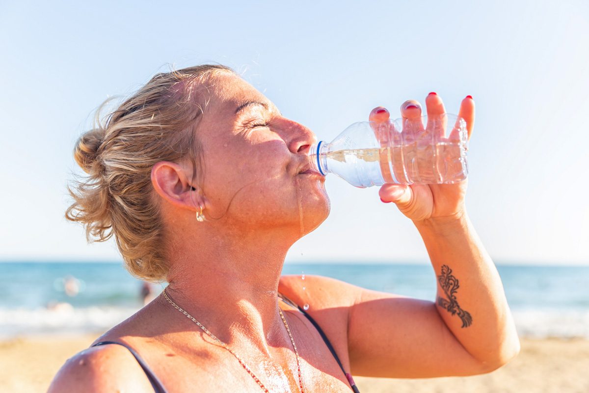 woman drinking water at the beach
